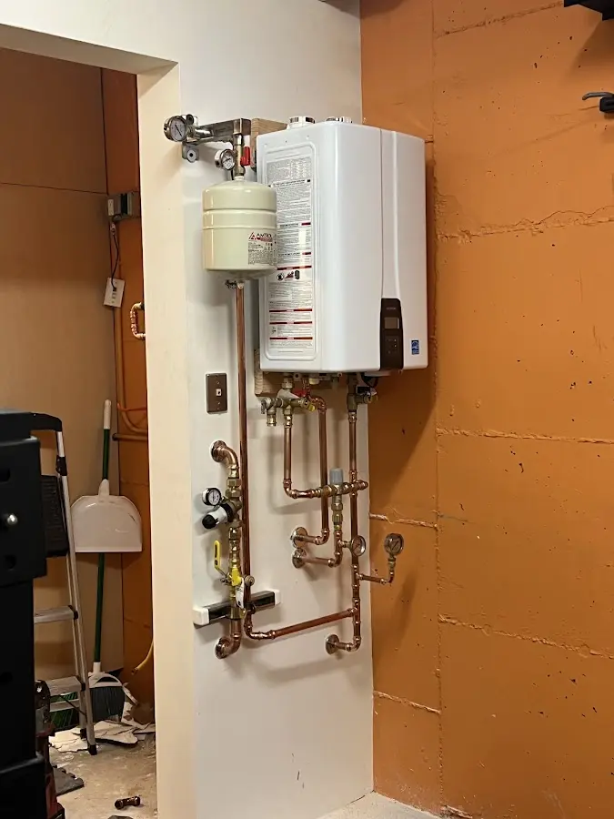 Plumbing technician inspecting water heater connections in North Hudson